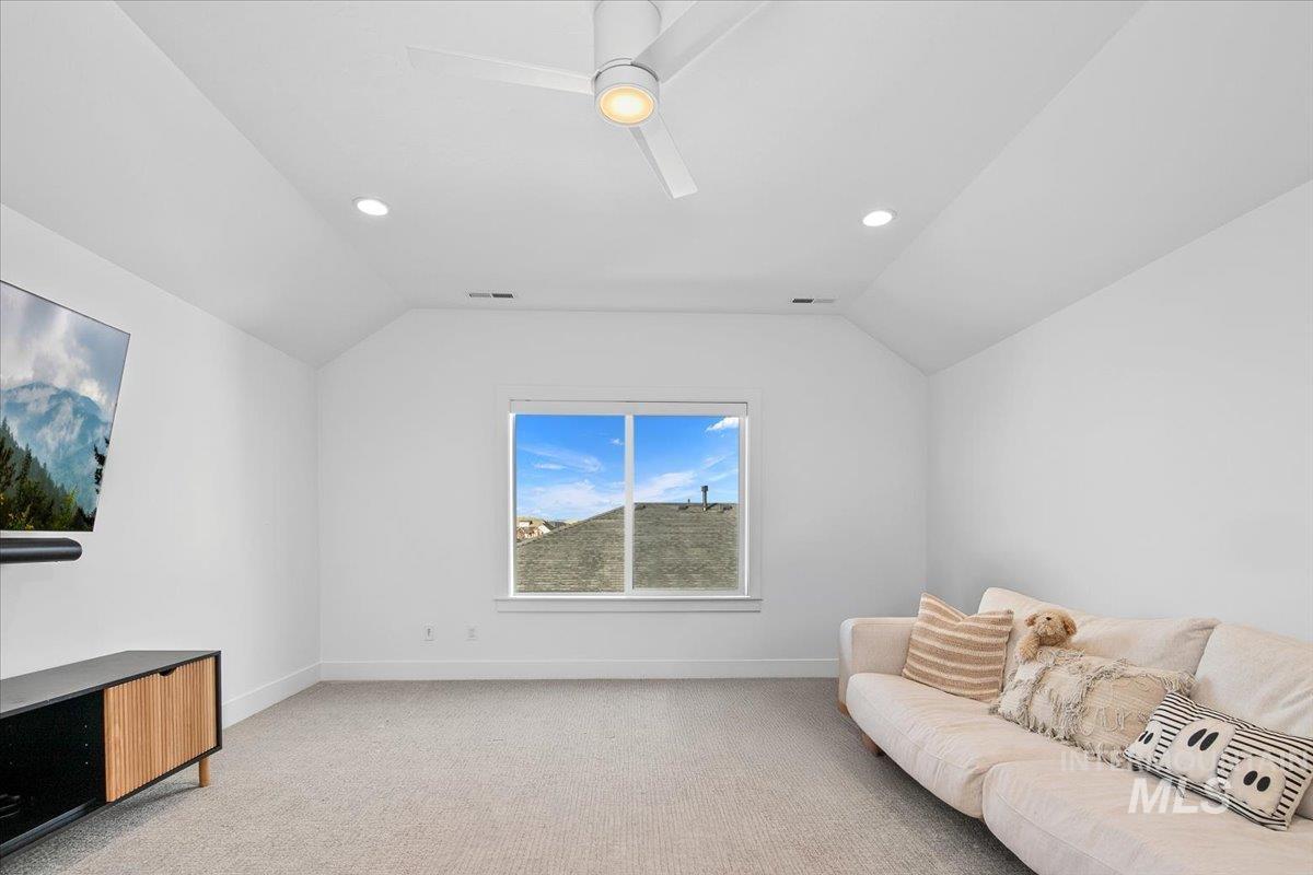 Living room featuring light carpet, vaulted ceiling, recessed lighting, and ceiling fan