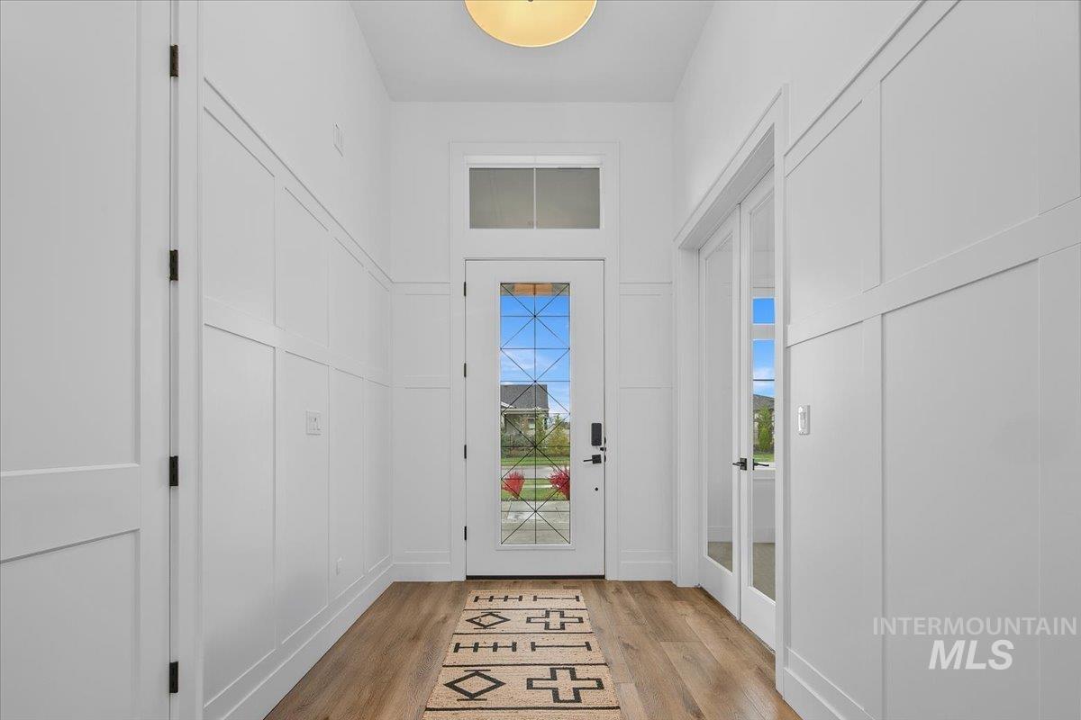 Doorway with wood finished floors and a decorative wall