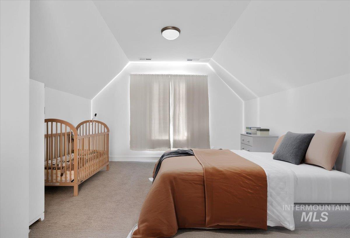 Bedroom with carpet floors and vaulted ceiling