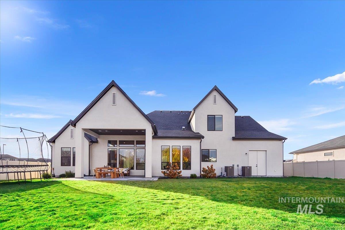 Back of house featuring a trampoline, stucco siding, and a patio area