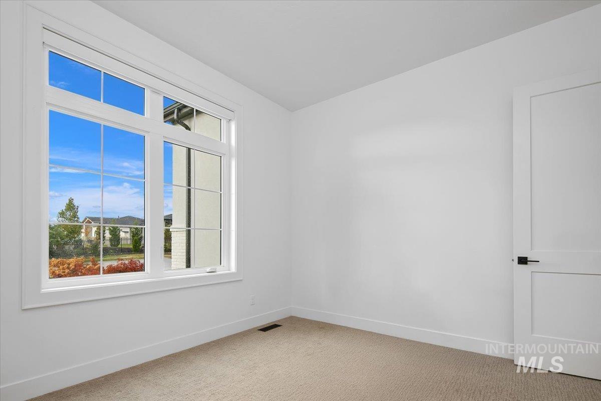 Unfurnished room featuring light carpet and baseboards