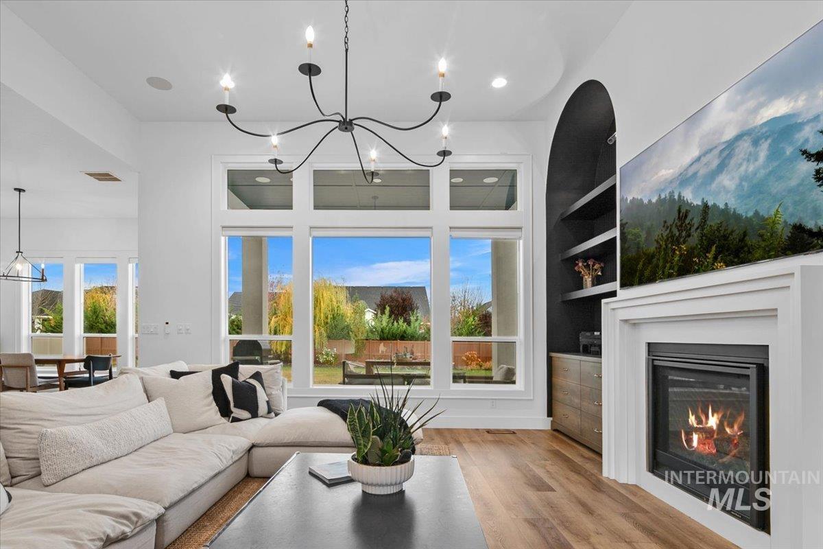 Living room featuring wood finished floors, a glass covered fireplace, healthy amount of natural light, built in features, and recessed lighting