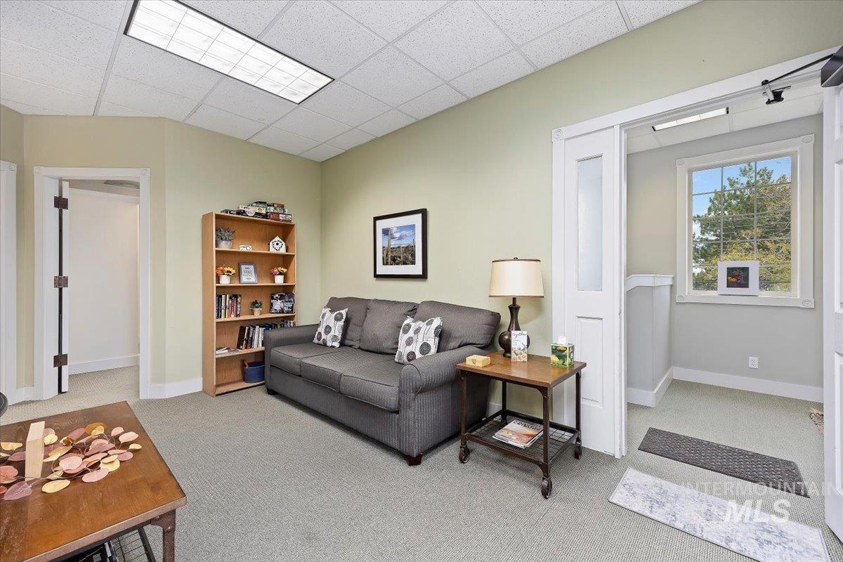 Living area with light colored carpet and a drop ceiling
