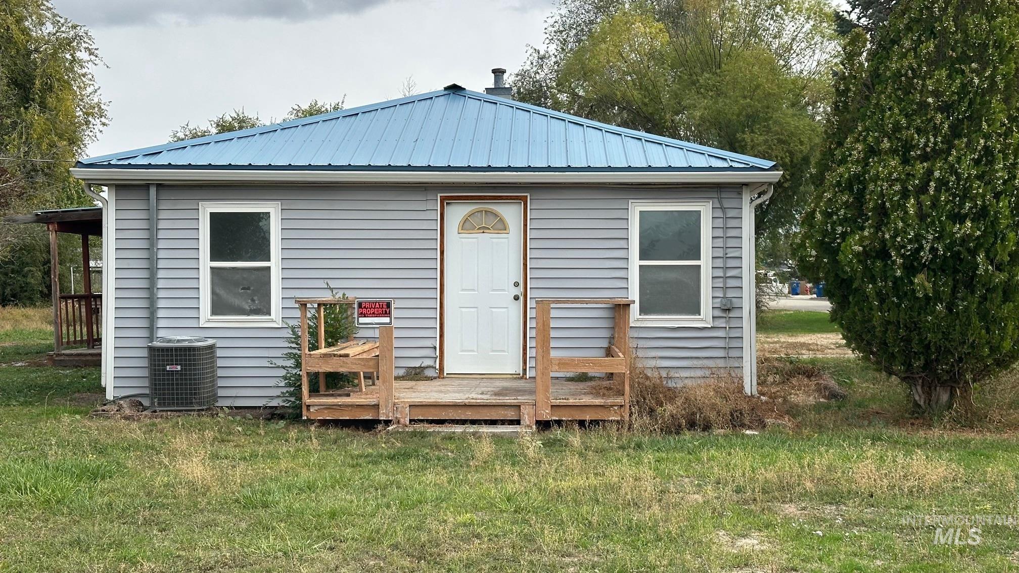 Rear view of house with a deck, a metal roof, and a yard