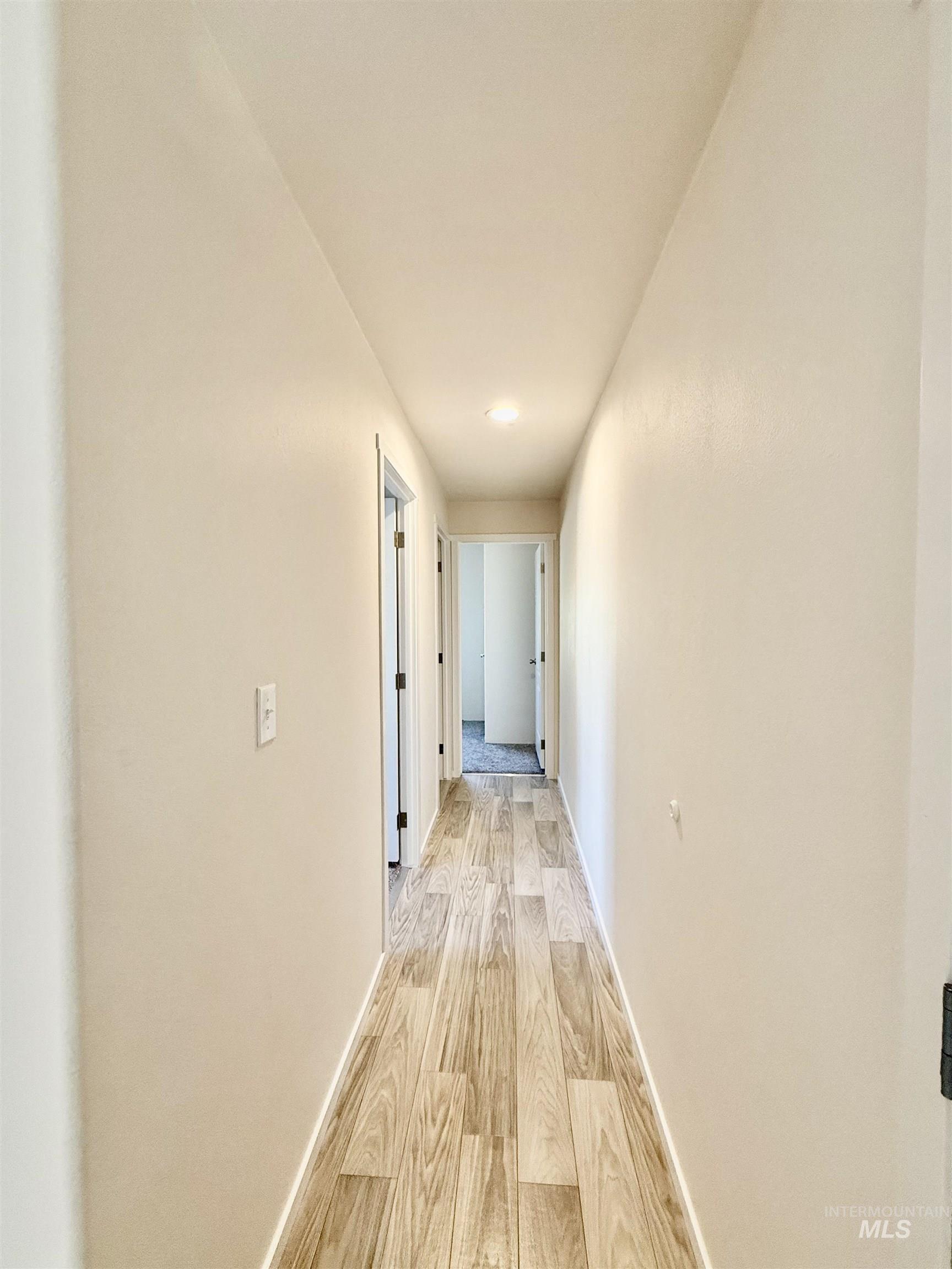 Hallway featuring light wood-type flooring and baseboards