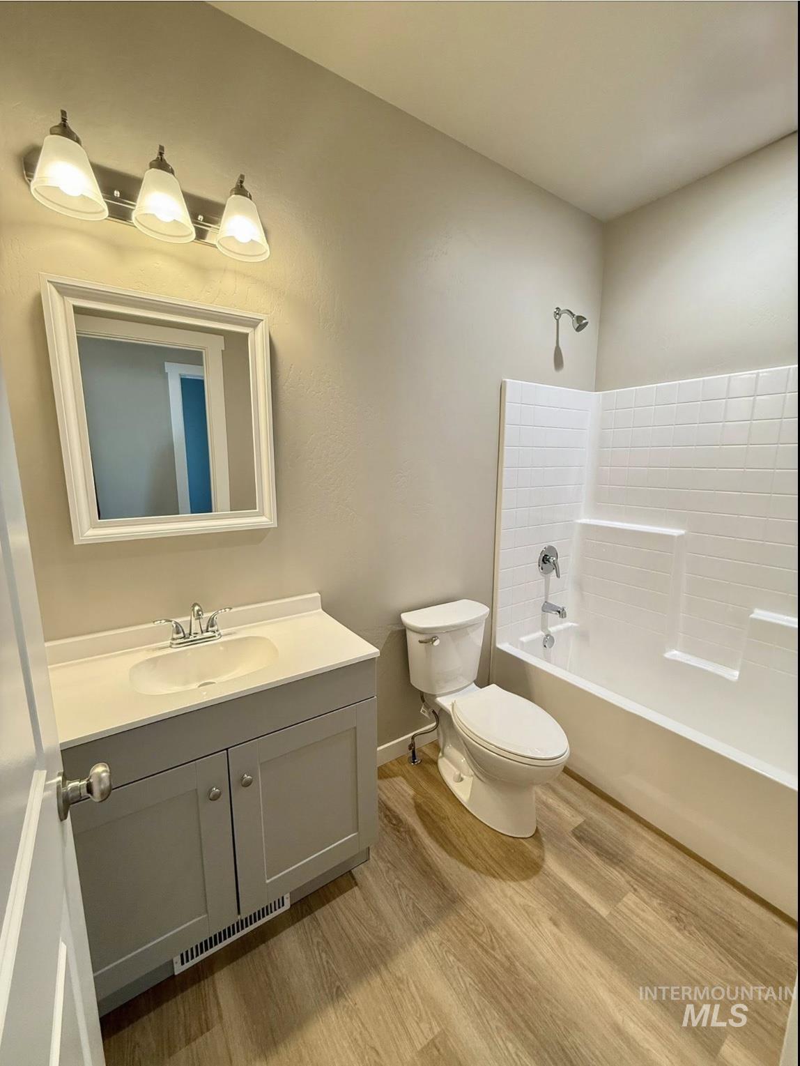 Bathroom with light wood finished floors, vanity, and shower / washtub combination