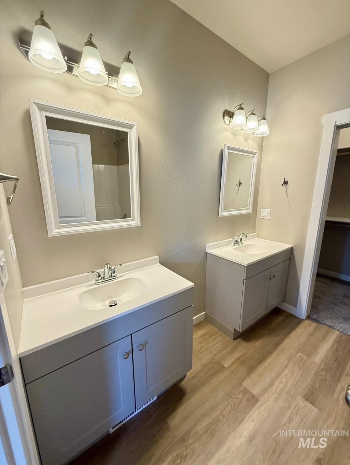 Bathroom featuring curtained shower, two vanities, and light wood-type flooring
