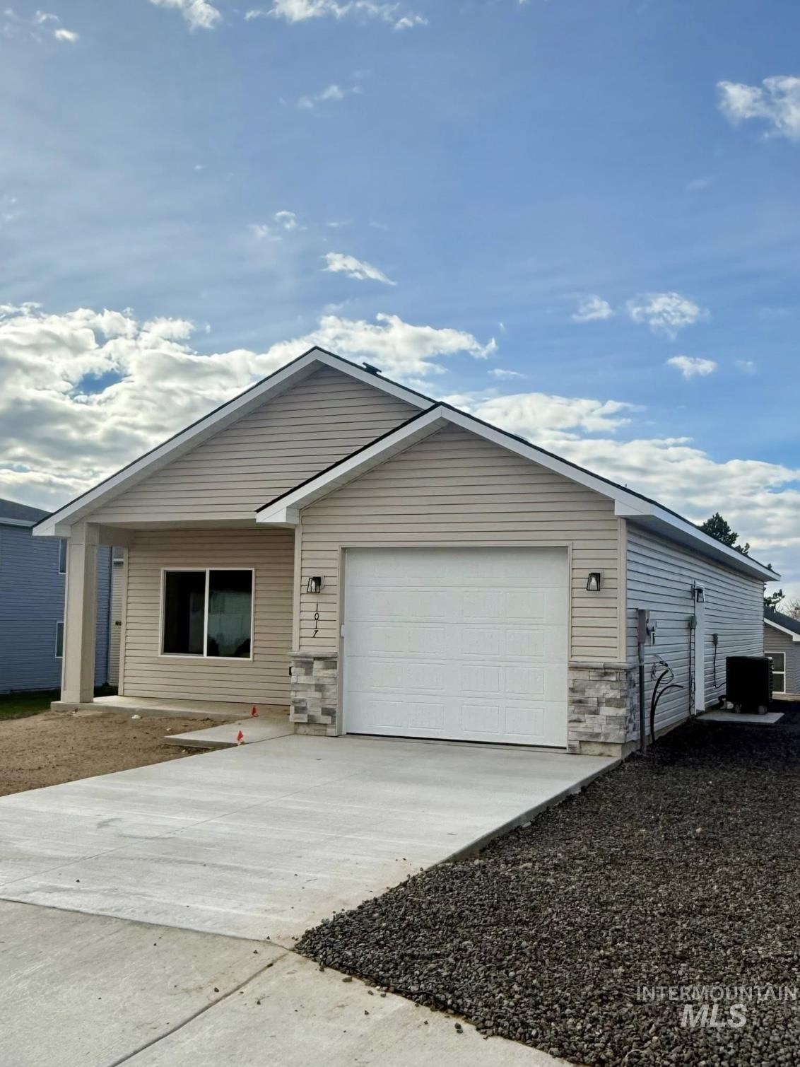 Ranch-style house featuring concrete driveway, stone siding, and a garage