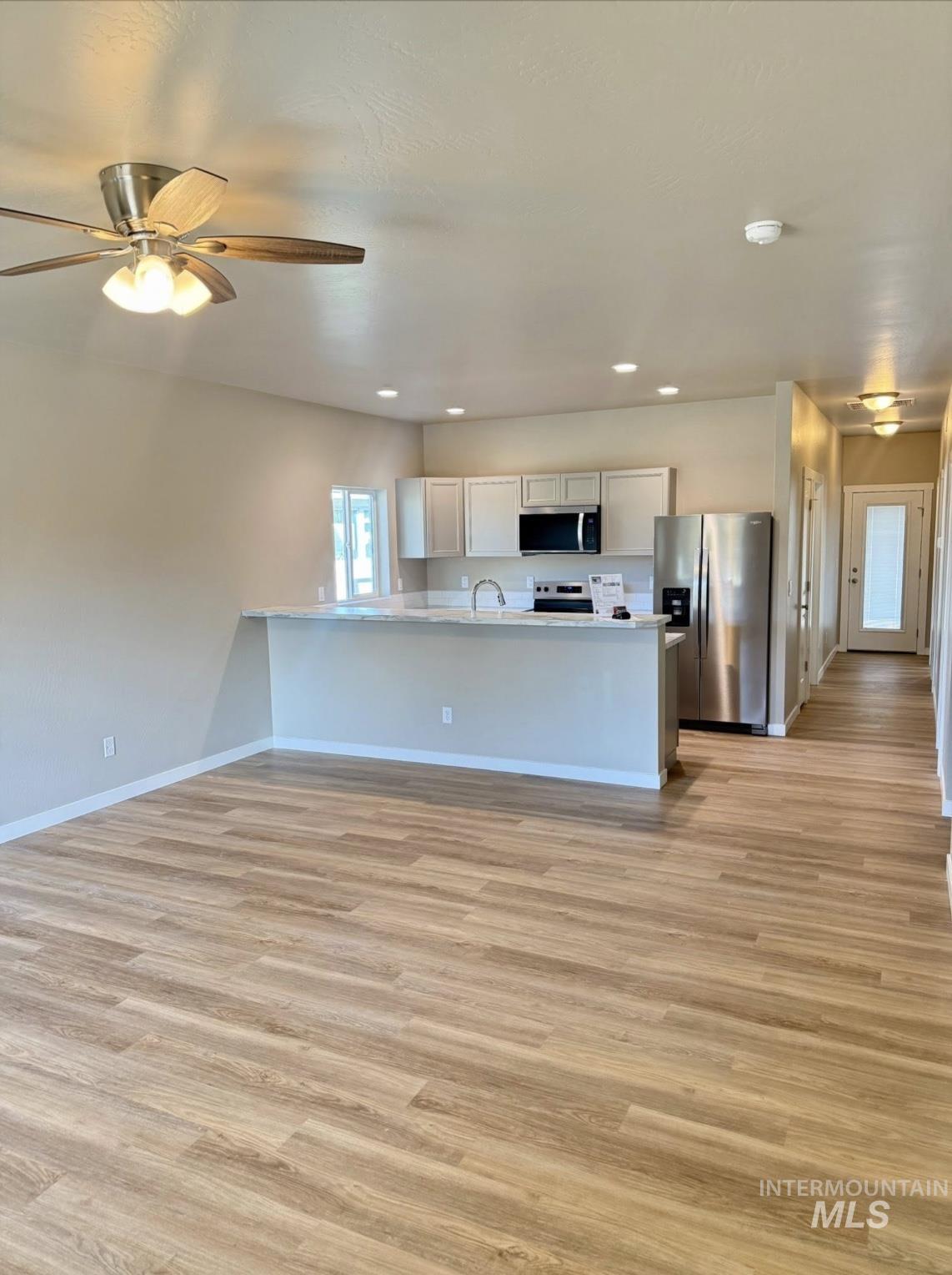 Kitchen with a peninsula, stainless steel appliances, light wood-style flooring, open floor plan, and recessed lighting