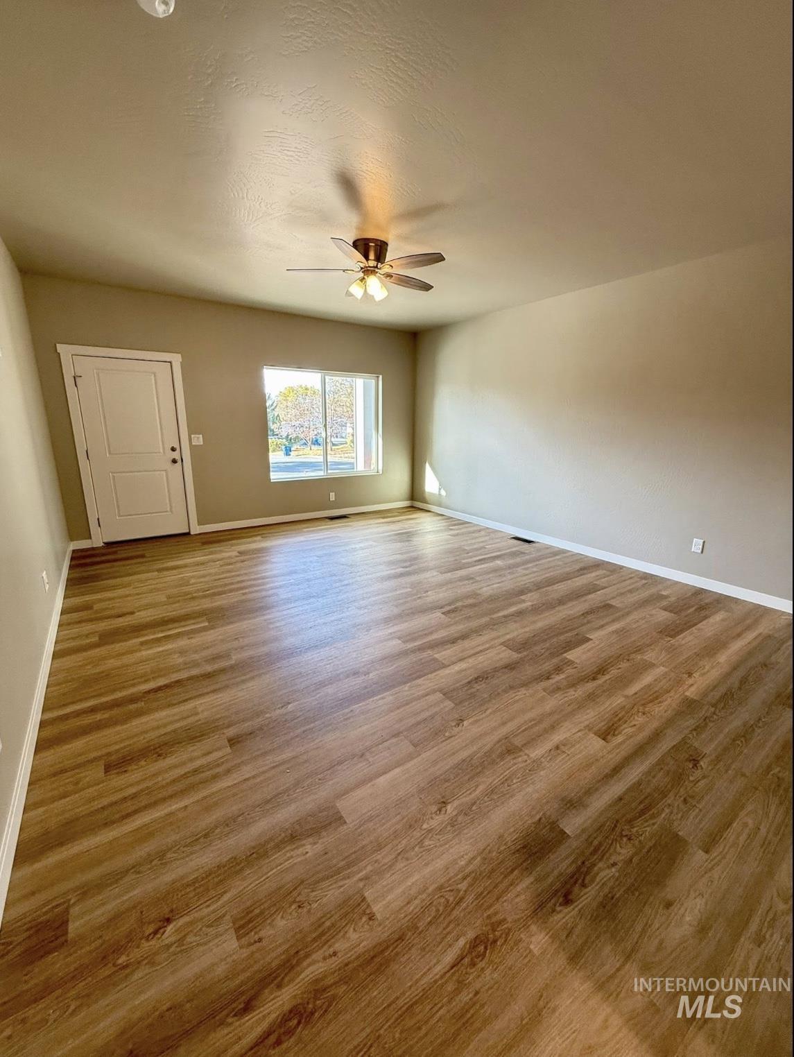 Spare room featuring light wood-style floors, a textured ceiling, and a ceiling fan