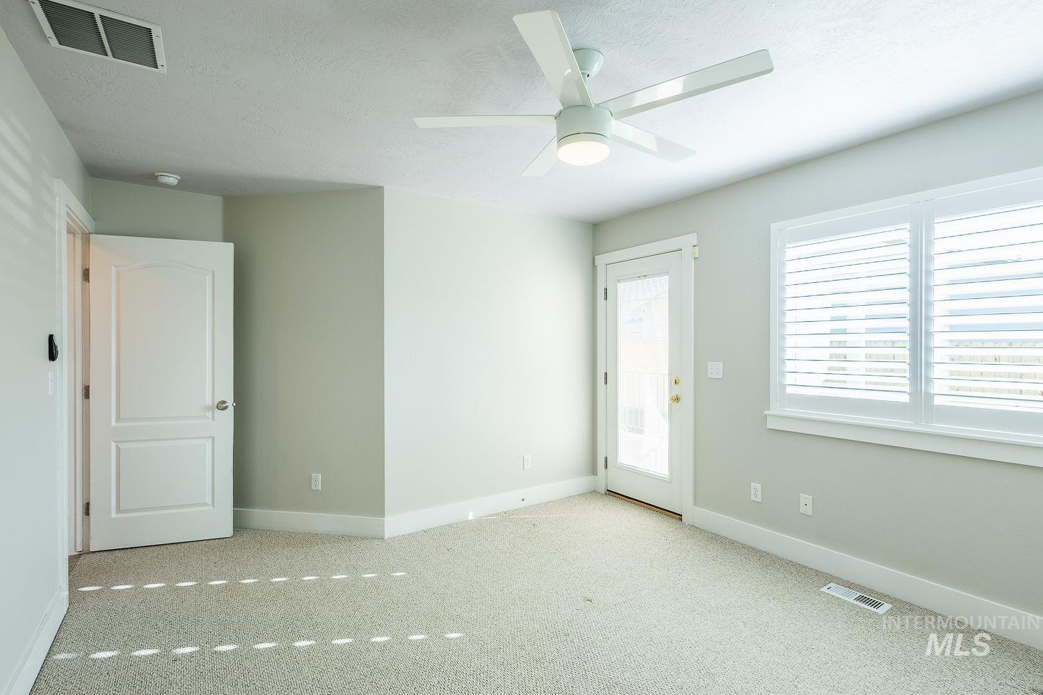 Carpeted spare room with a textured ceiling and a ceiling fan
