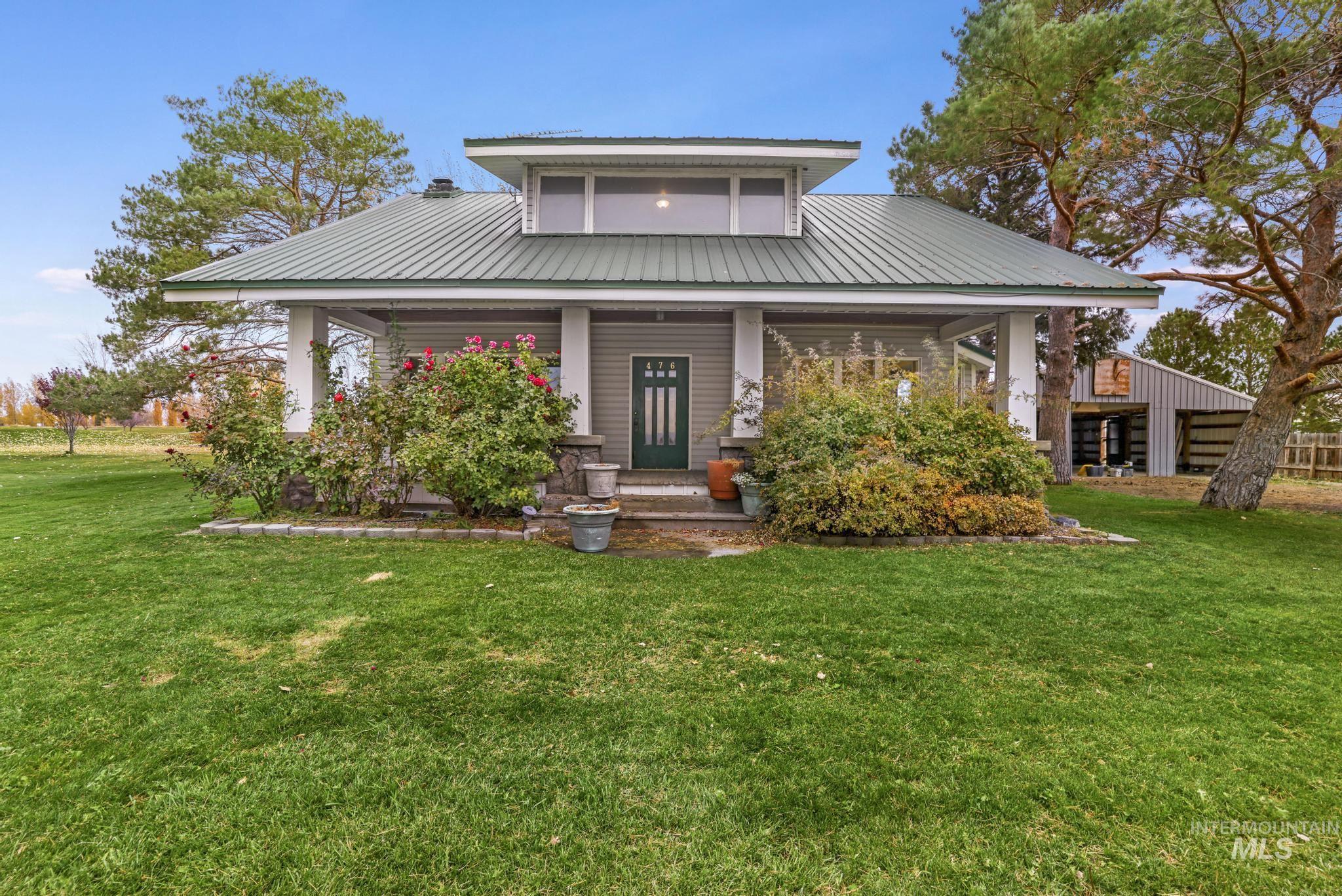 View of front facade featuring covered porch, a front yard, and a metal roof