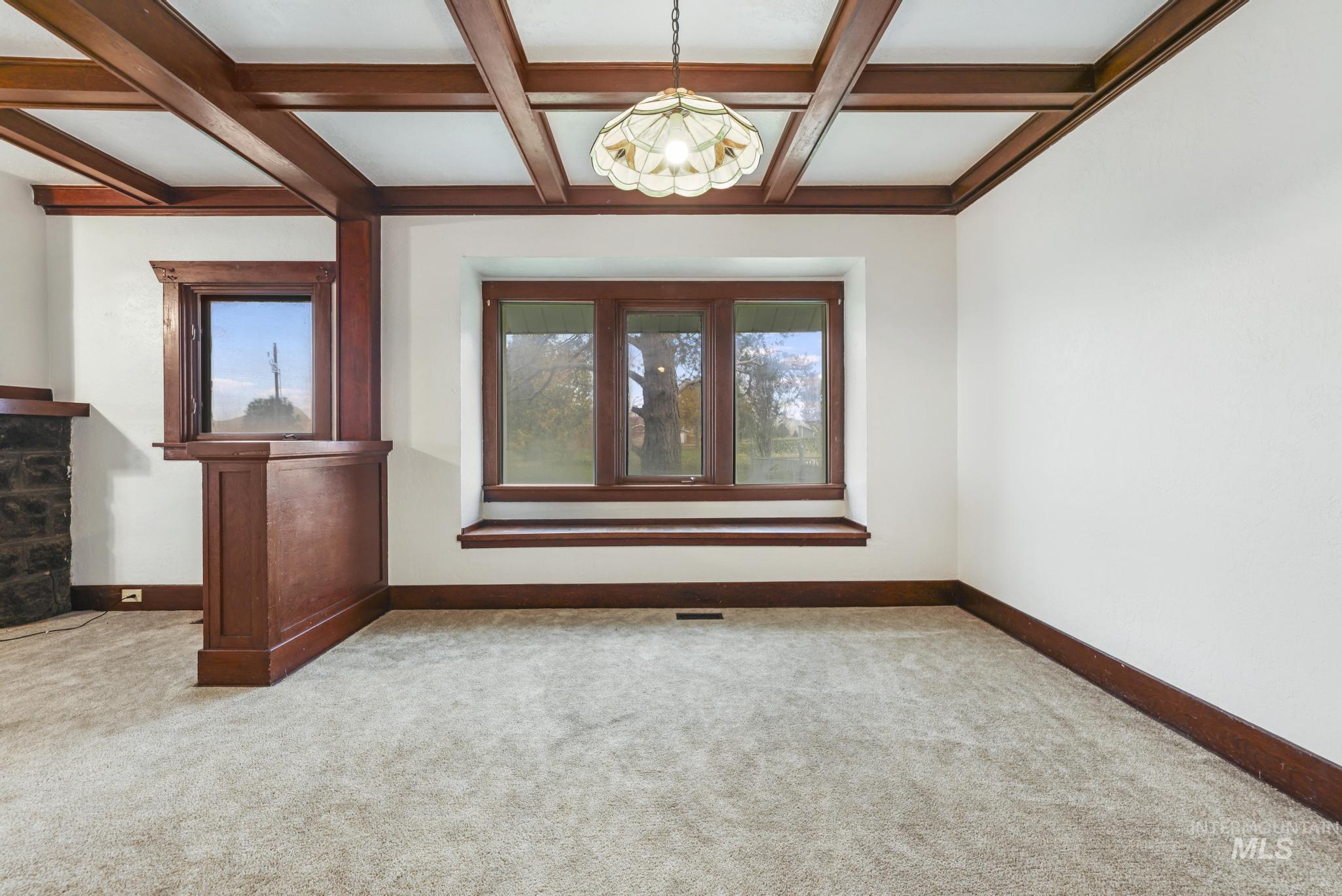 Spare room featuring coffered ceiling, beam ceiling, and light carpet