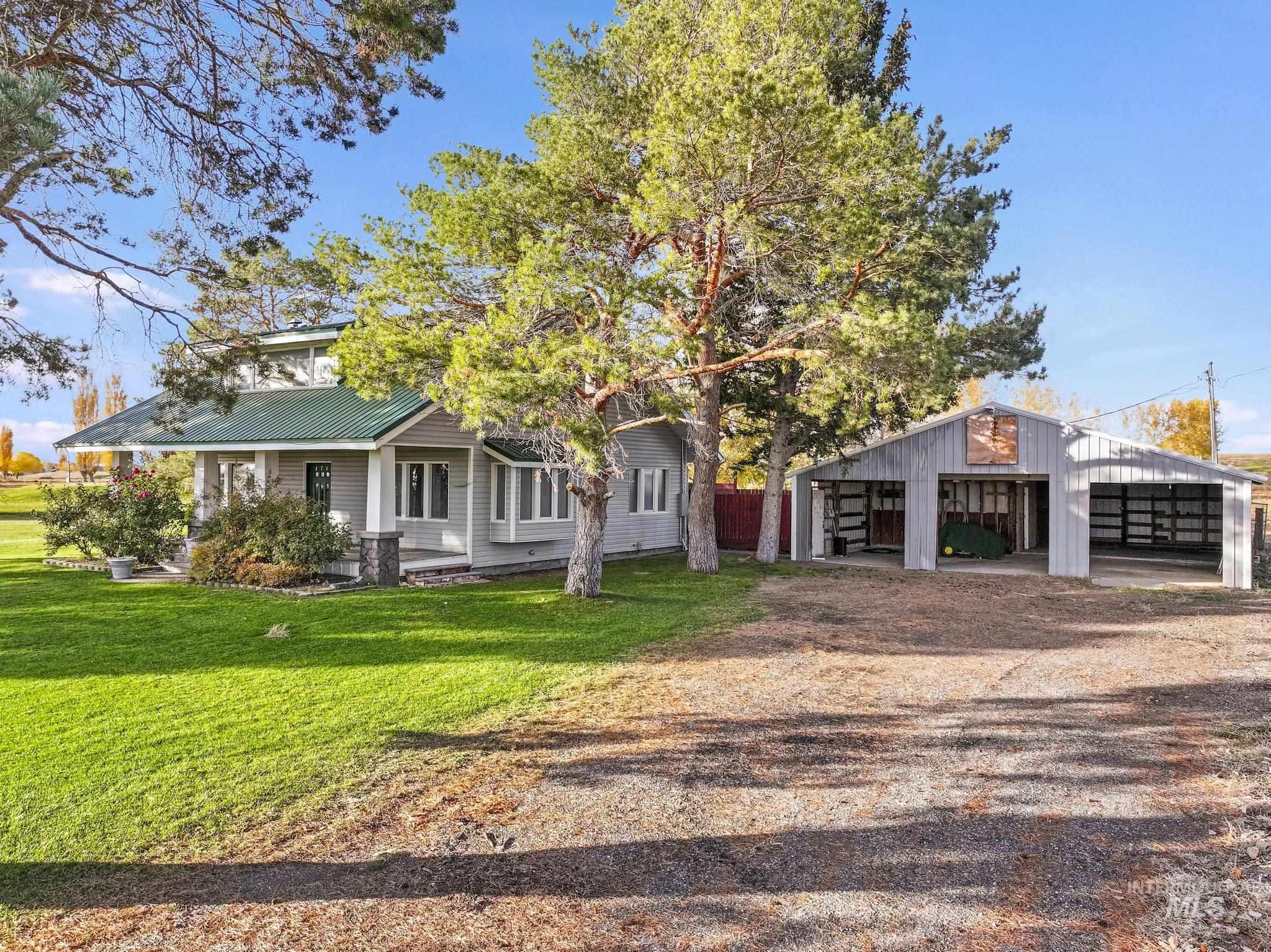 View of front of property featuring a pole building, an outbuilding, a metal roof, a porch, and a front lawn