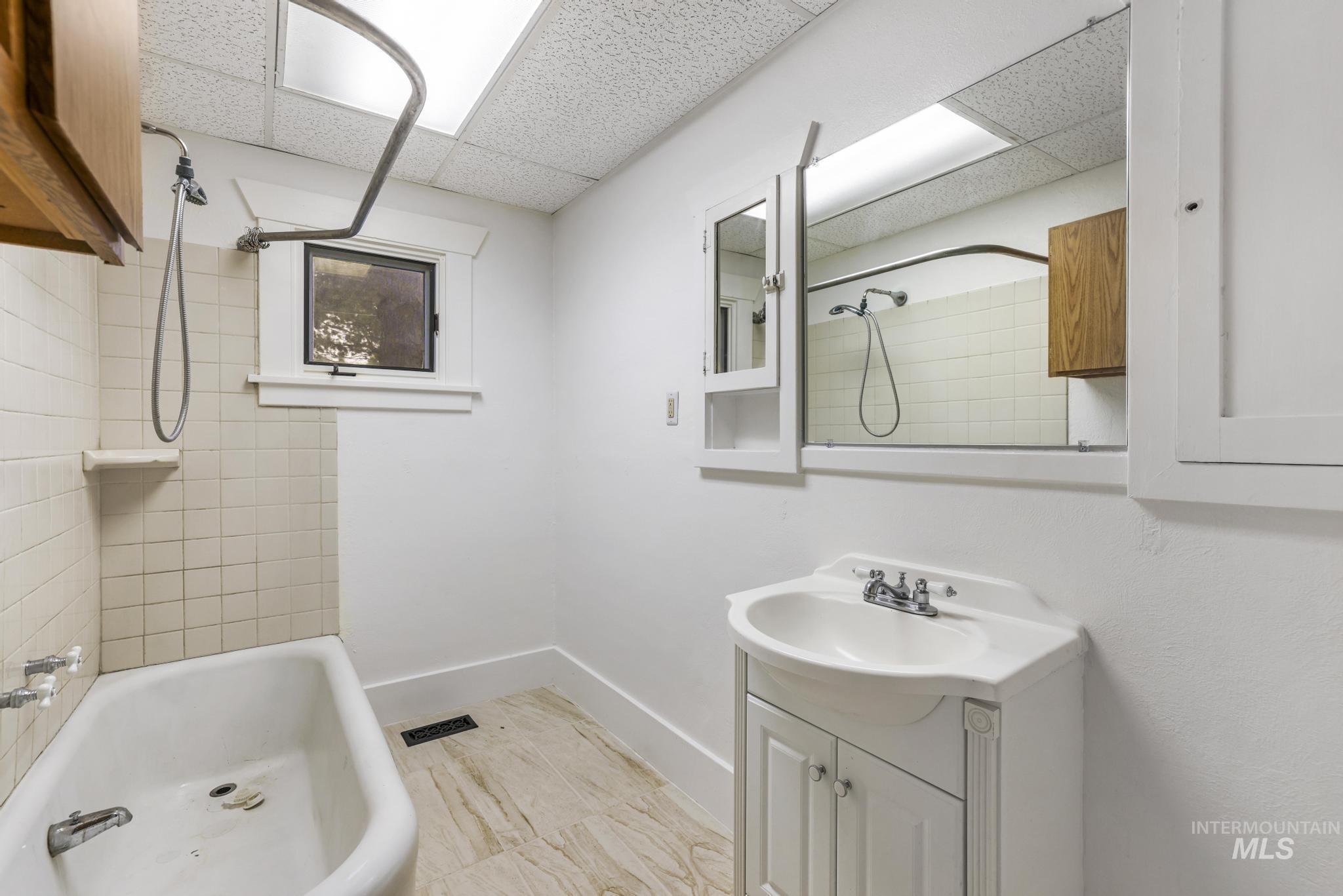Full bath featuring vanity, shower / bath combination, and a drop ceiling