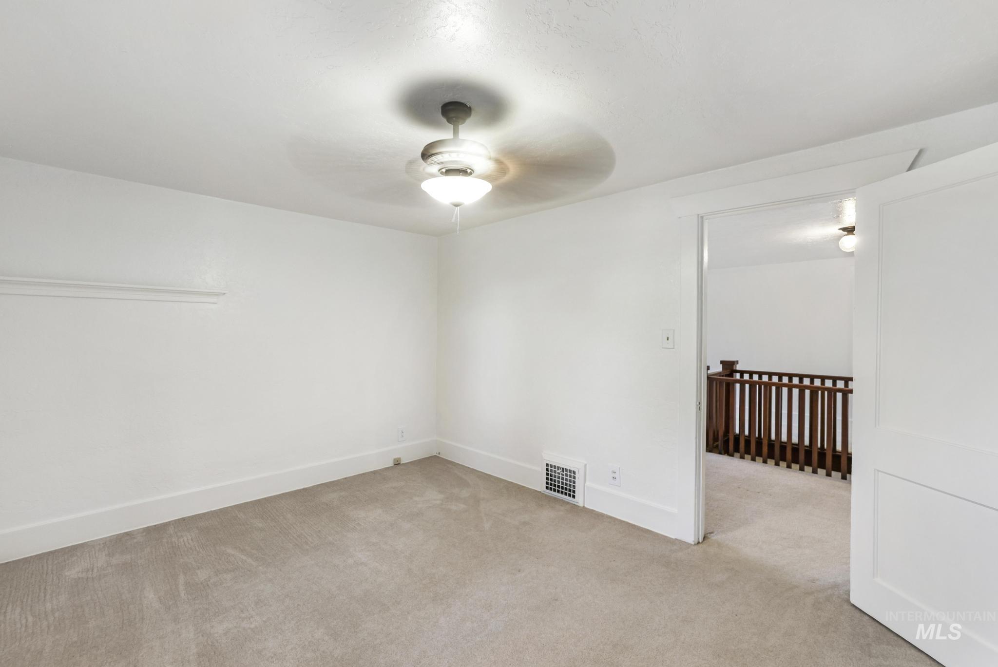 Unfurnished room with light colored carpet and a ceiling fan