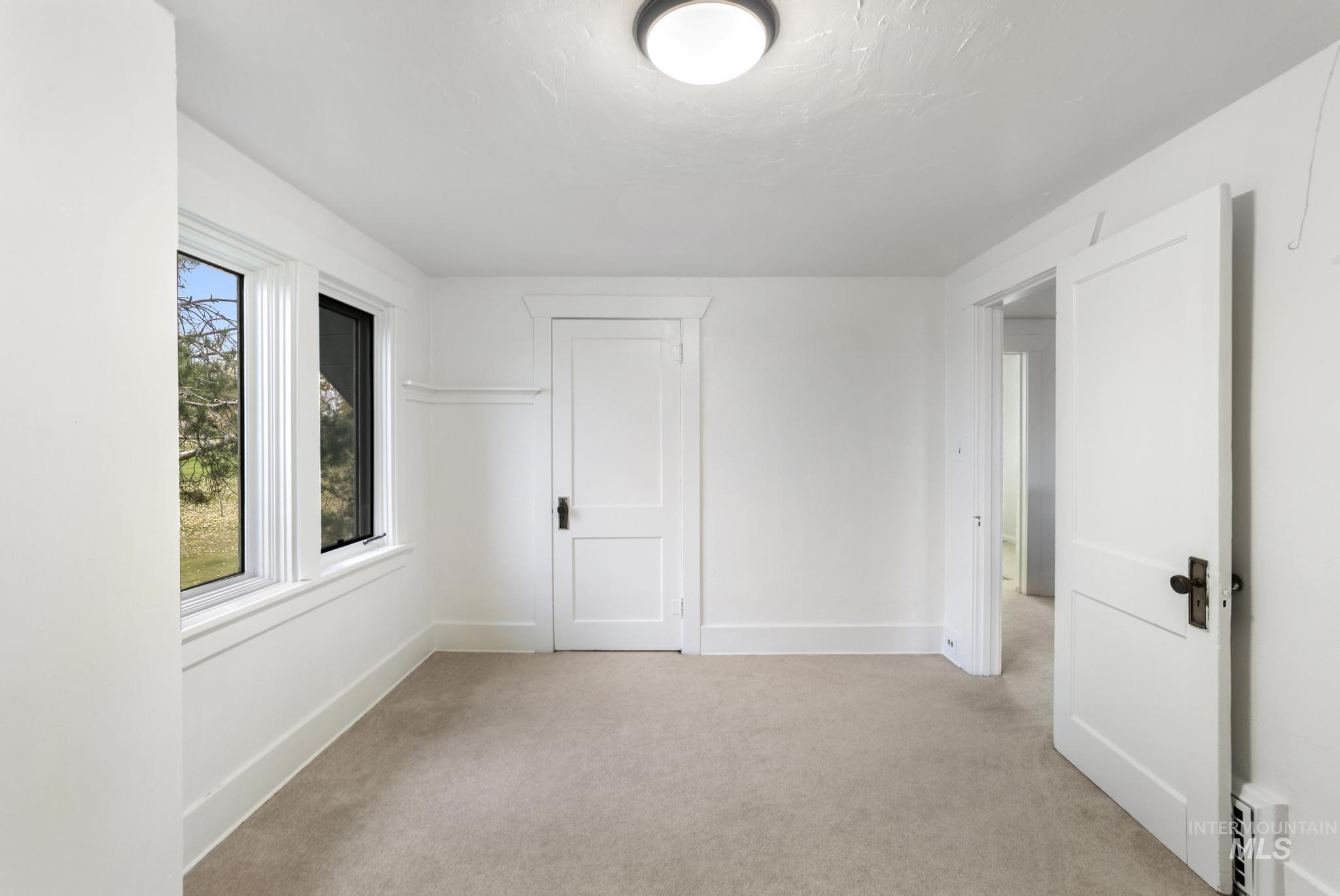 Unfurnished room featuring light carpet and baseboards