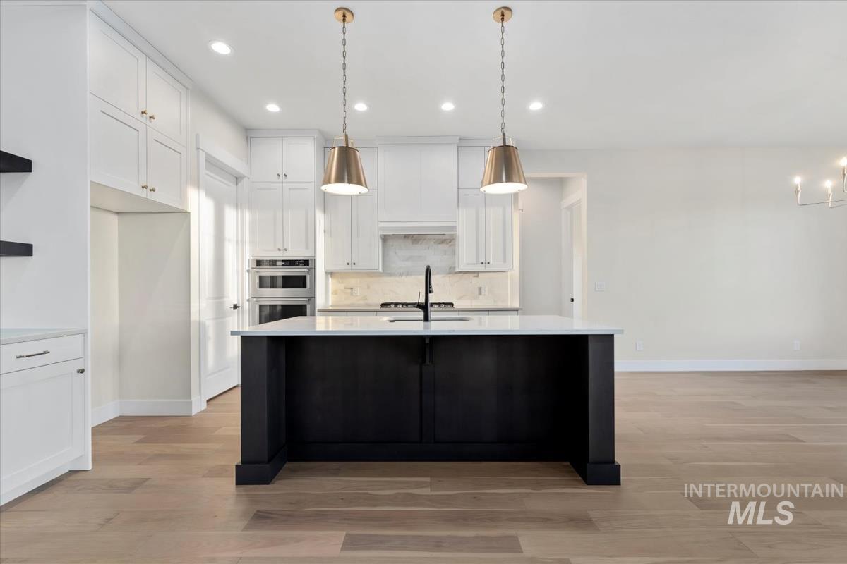 Kitchen featuring white cabinets, hanging light fixtures, light wood finished floors, and recessed lighting