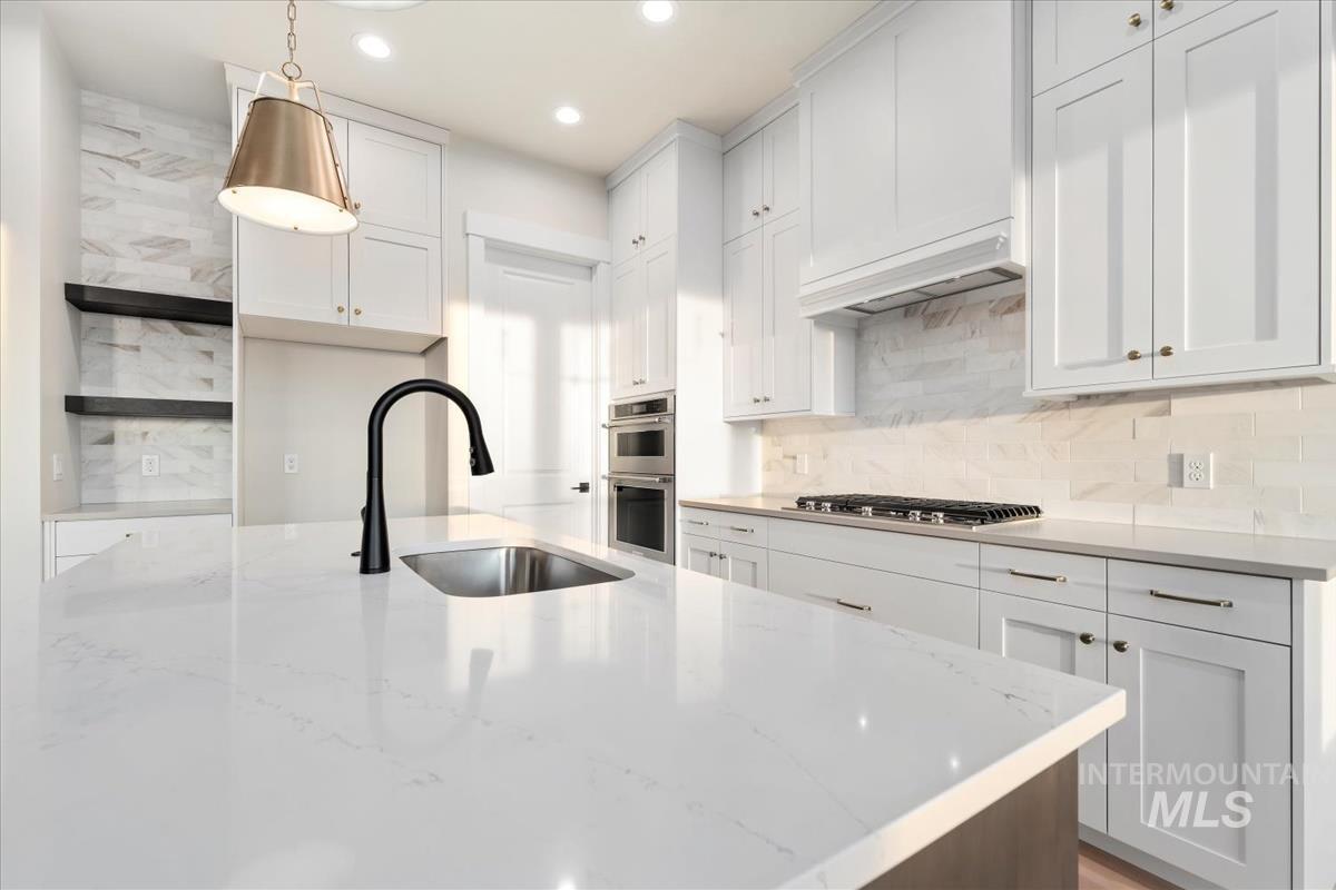 Kitchen featuring light stone counters, hanging light fixtures, open shelves, white cabinetry, and recessed lighting