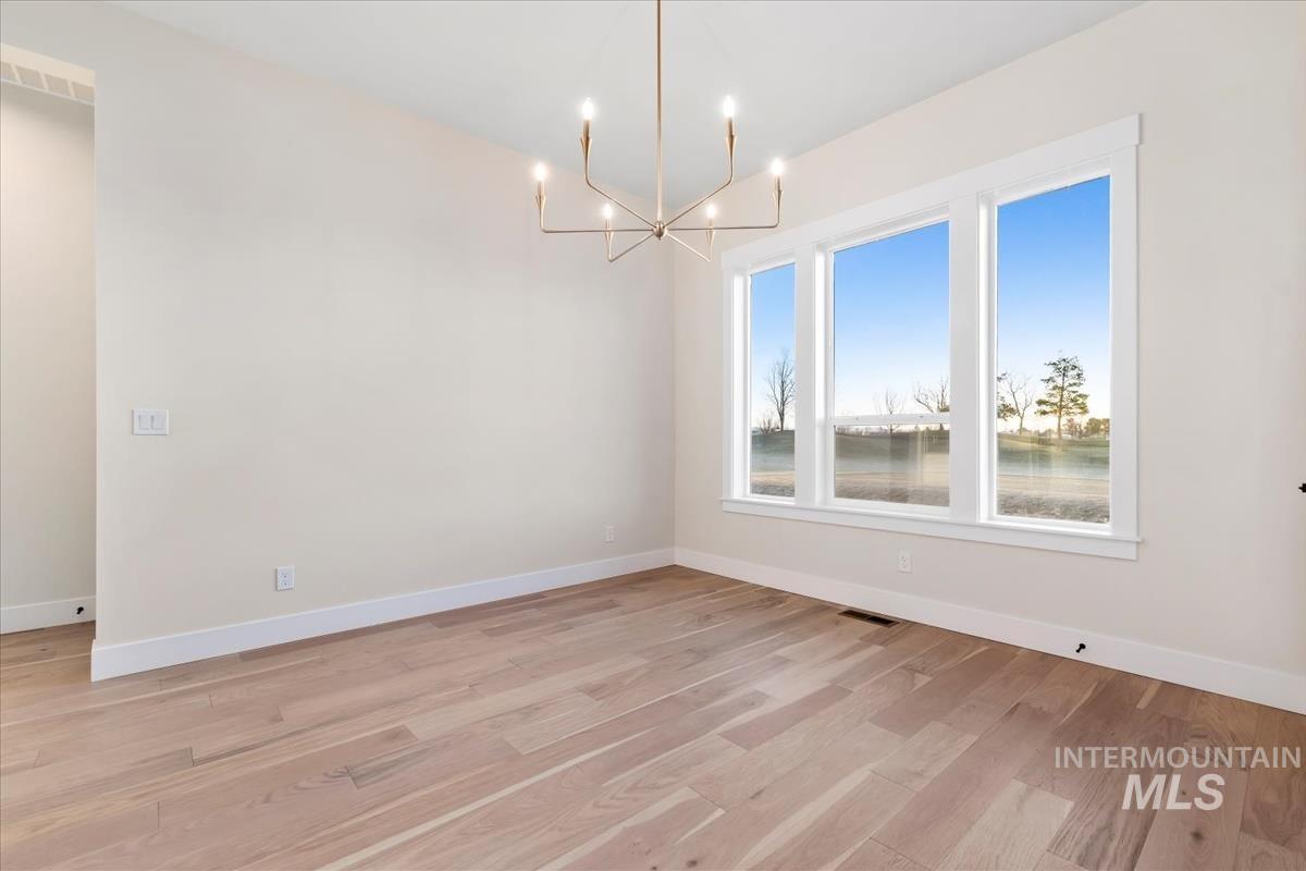 Empty room featuring light wood-type flooring and a chandelier