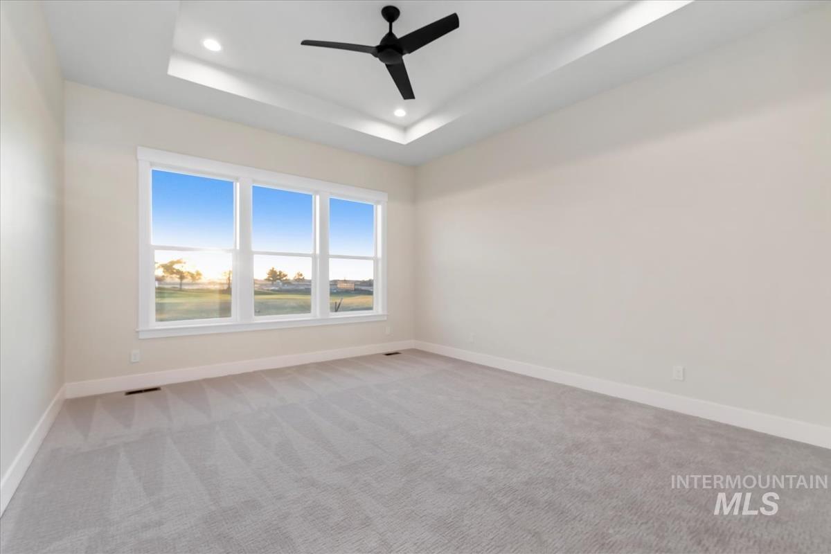 Unfurnished room featuring a tray ceiling, light carpet, ceiling fan, and recessed lighting