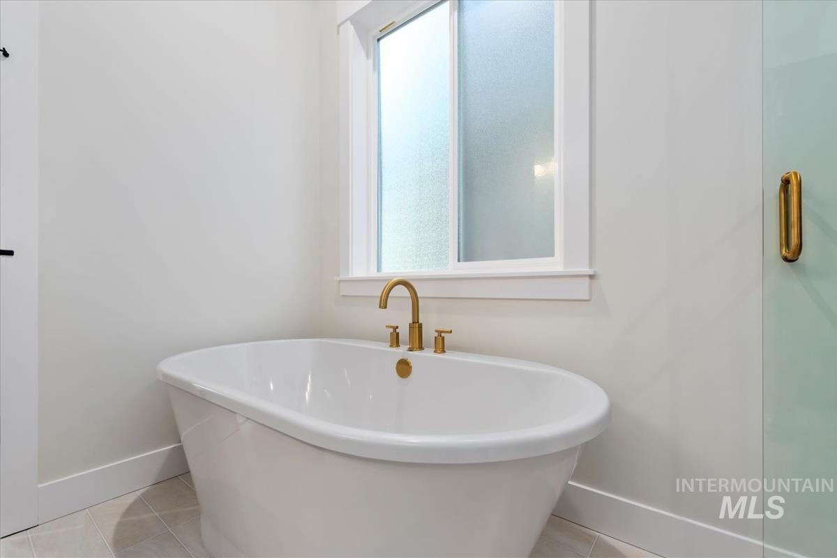 Full bathroom with light tile patterned floors and a soaking tub