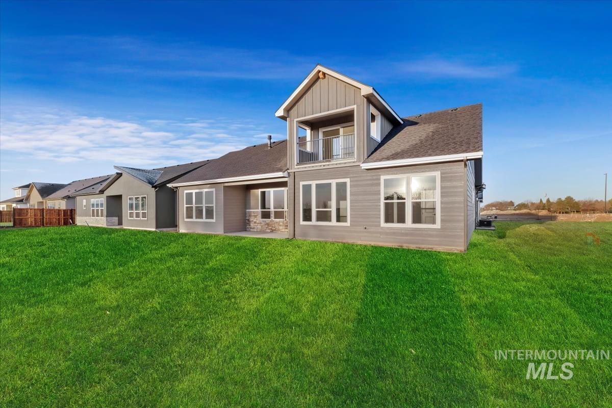 Back of property with a balcony, a lawn, a patio area, and roof with shingles