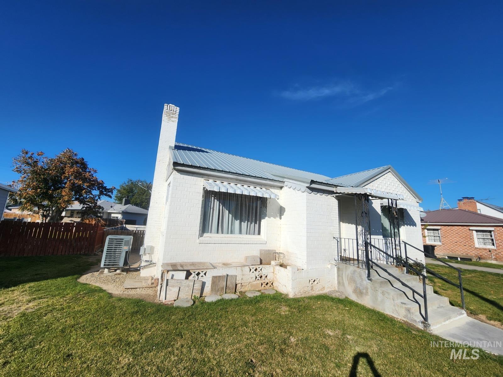 Back of property featuring a metal roof, a chimney, and brick siding
