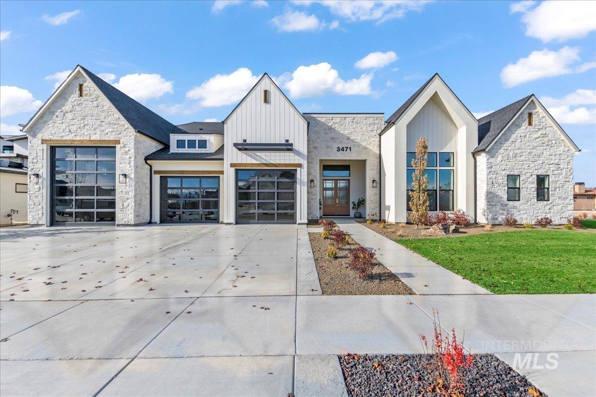 View of front of home with stone siding, concrete driveway, board and batten siding, and an attached garage