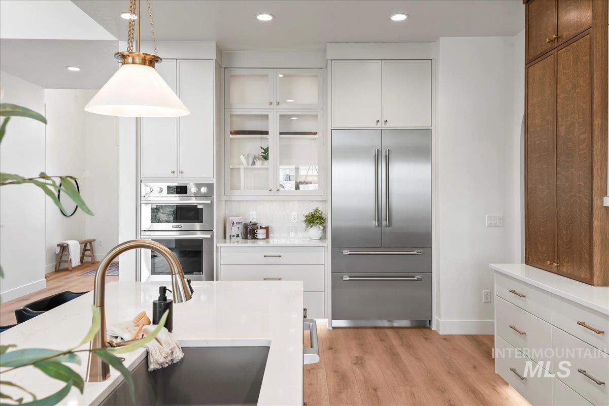 Kitchen featuring white cabinetry, stainless steel appliances, pendant lighting, light wood-style floors, and recessed lighting