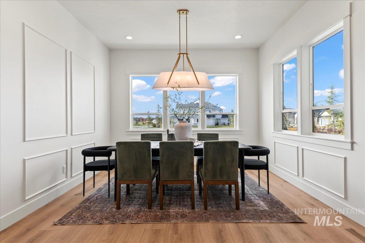 Dining area featuring light wood finished floors, a decorative wall, and recessed lighting