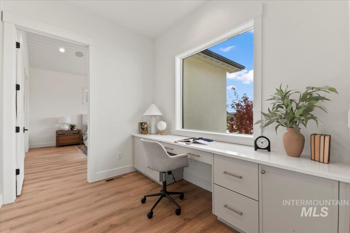 Office with built in study area and light wood finished floors