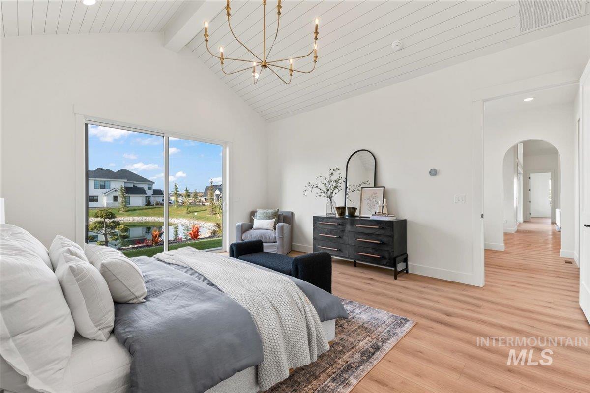Bedroom with arched walkways, wood finished floors, access to outside, recessed lighting, and a chandelier
