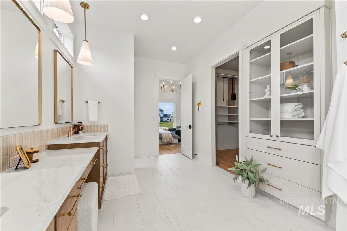 Ensuite bathroom featuring recessed lighting, vanity, a chandelier, and a spacious closet