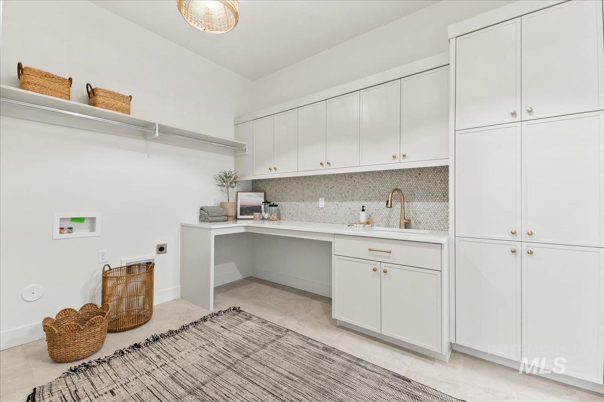 Washroom with electric dryer hookup, washer hookup, light tile patterned floors, and cabinet space