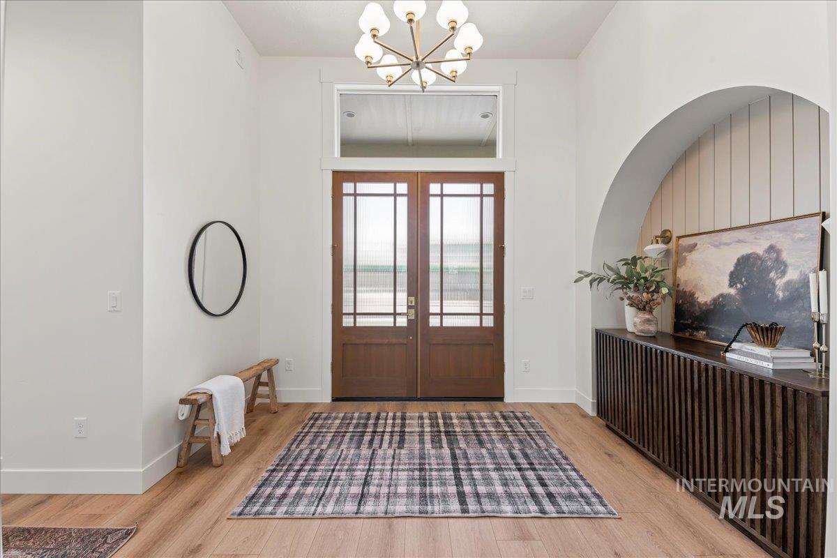 Foyer with wood finished floors, a chandelier, french doors, and radiator heating unit