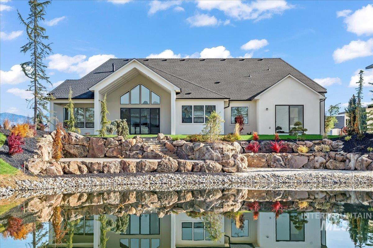 Rear view of house featuring roof with shingles and stucco siding