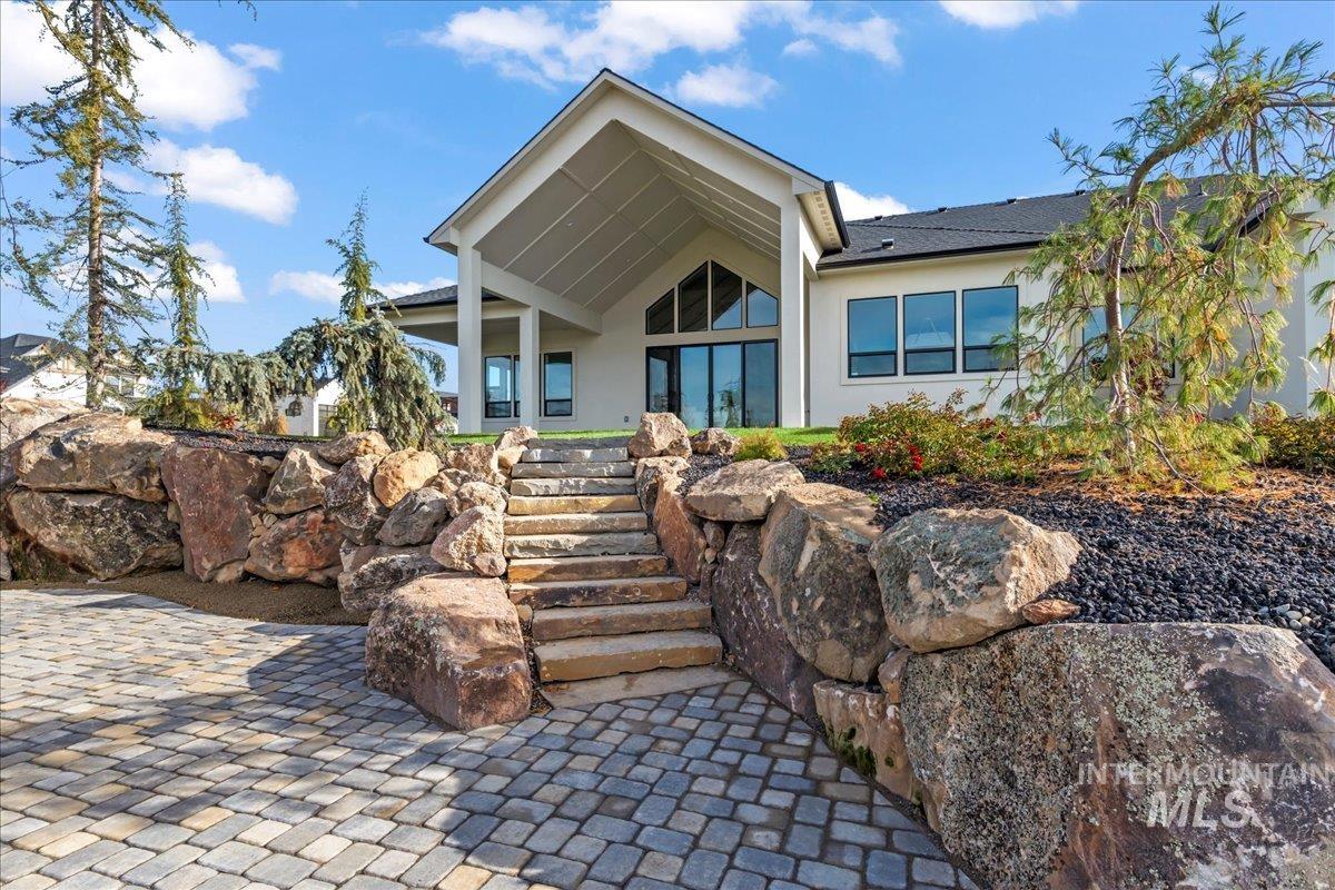 Rear view of property featuring a patio area, stairs, and stucco siding
