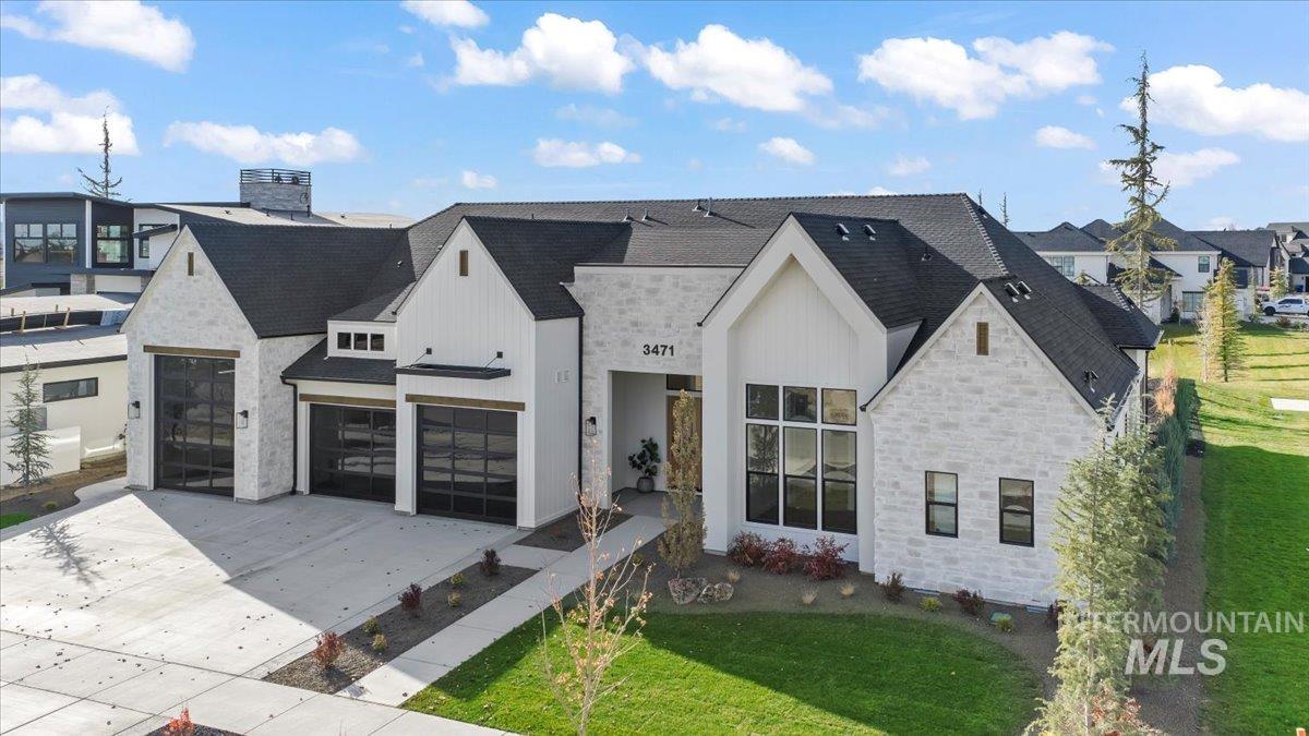 View of front of house featuring stone siding, driveway, a shingled roof, and a front yard