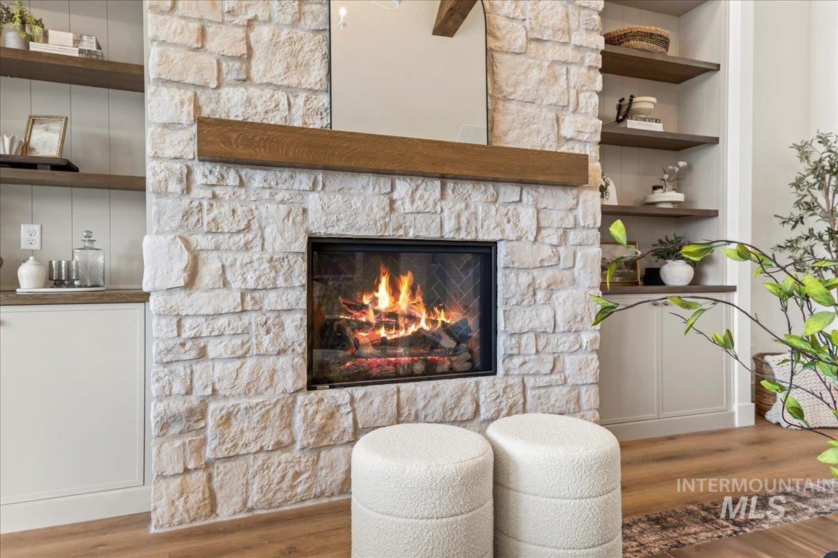 Detailed view of wood finished floors, a stone fireplace, and built in features