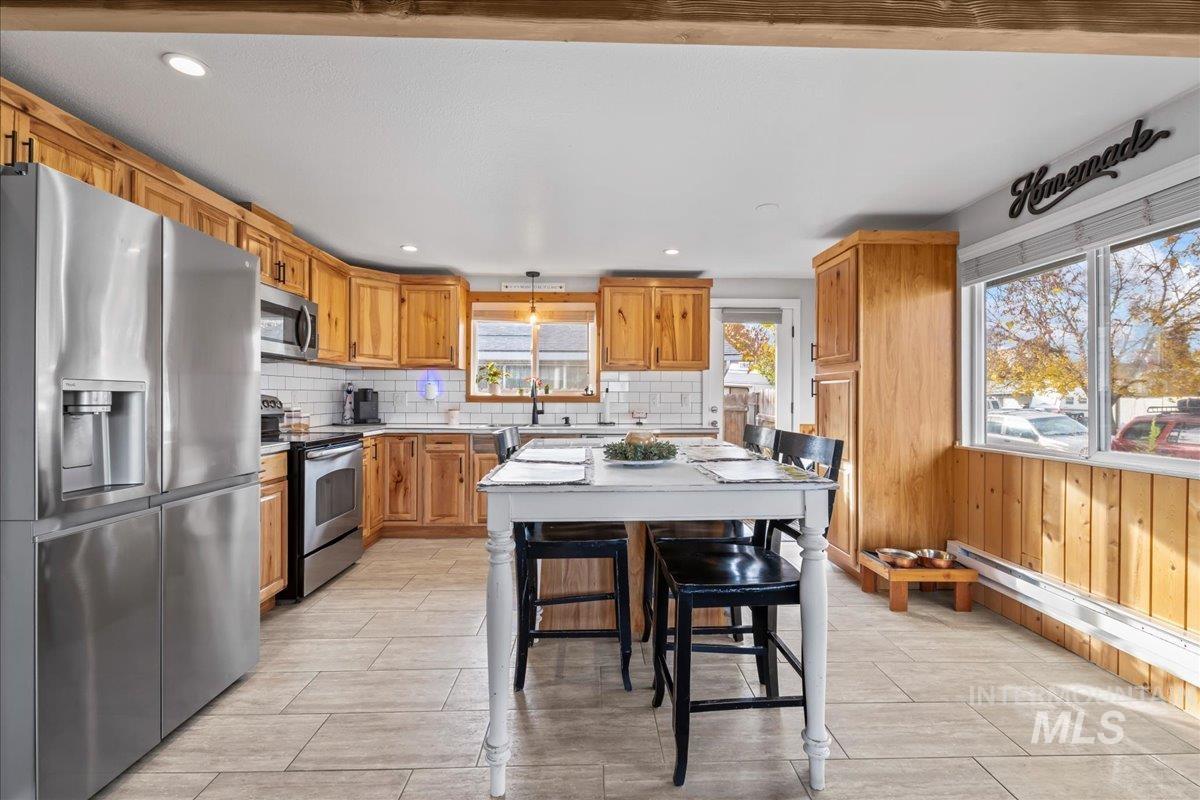 Kitchen with stainless steel appliances, light countertops, decorative backsplash, recessed lighting, and pendant lighting