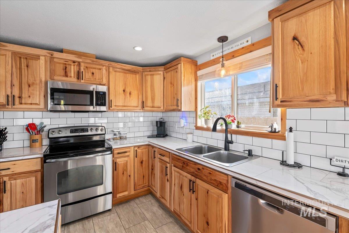 Kitchen with stainless steel appliances, tasteful backsplash, pendant lighting, brown cabinetry, and recessed lighting