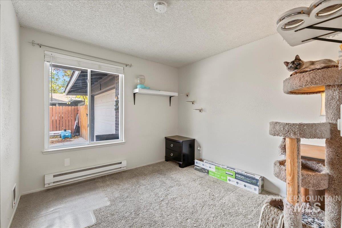Interior space featuring a baseboard radiator, carpet floors, and a textured ceiling