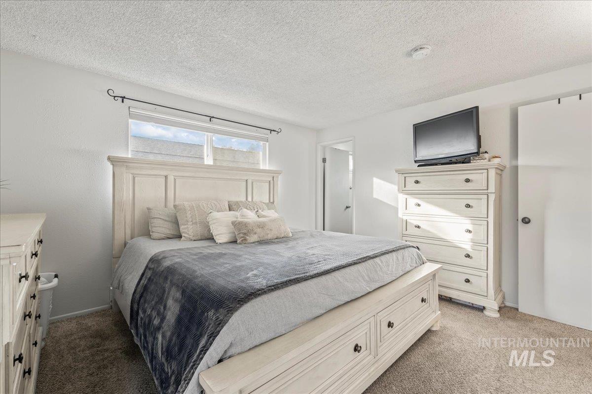Bedroom featuring light colored carpet and a textured ceiling