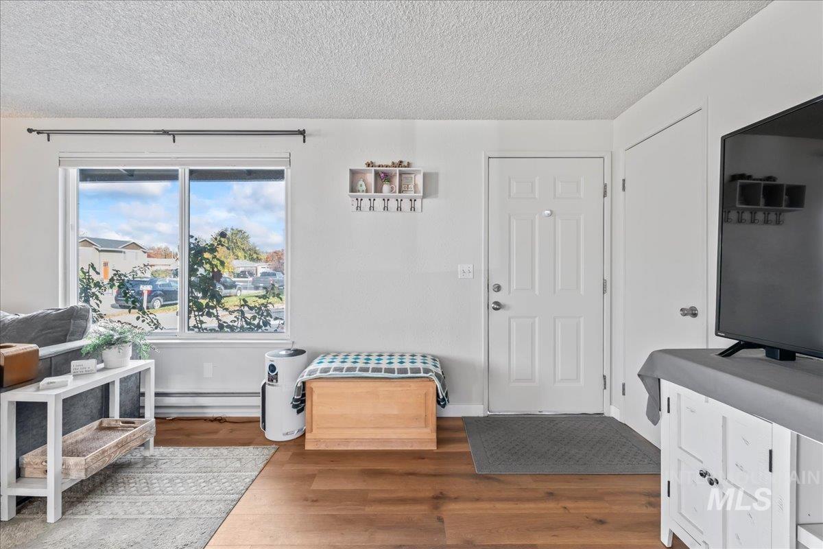 Foyer with wood finished floors, a textured ceiling, and a baseboard heating unit