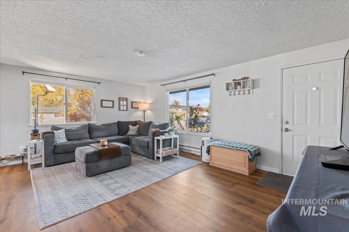 Living area featuring dark wood-style floors, a textured ceiling, and a baseboard heating unit