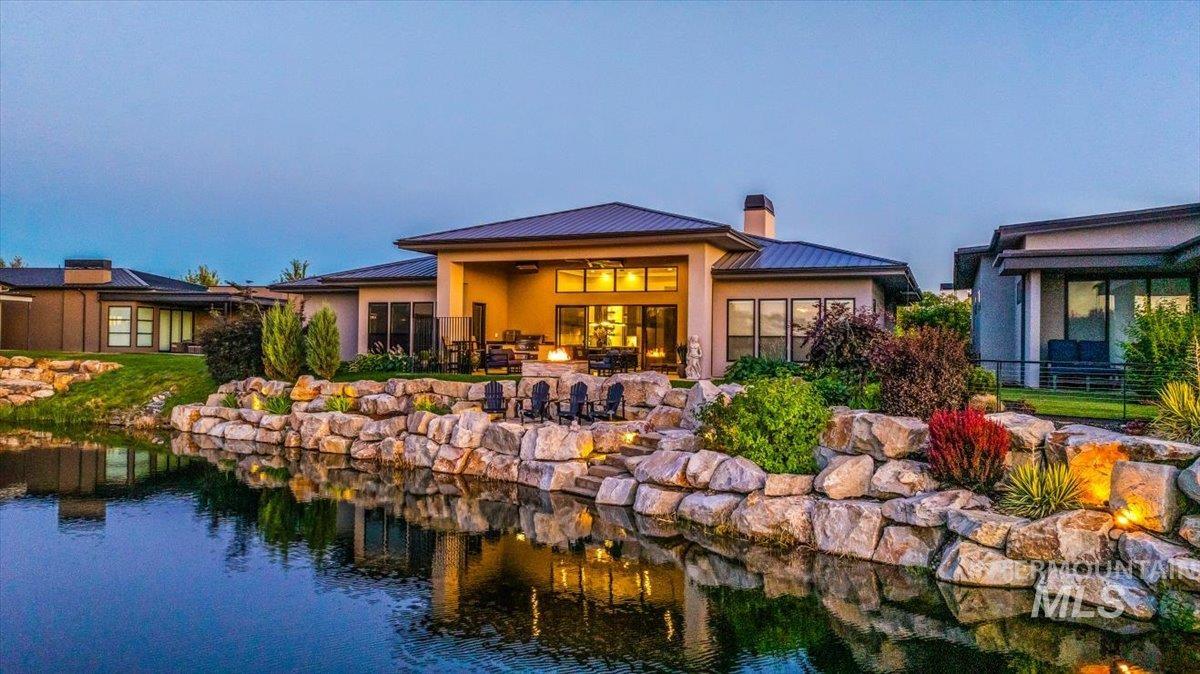 Back of house with a metal roof, a chimney, stucco siding, and a standing seam roof