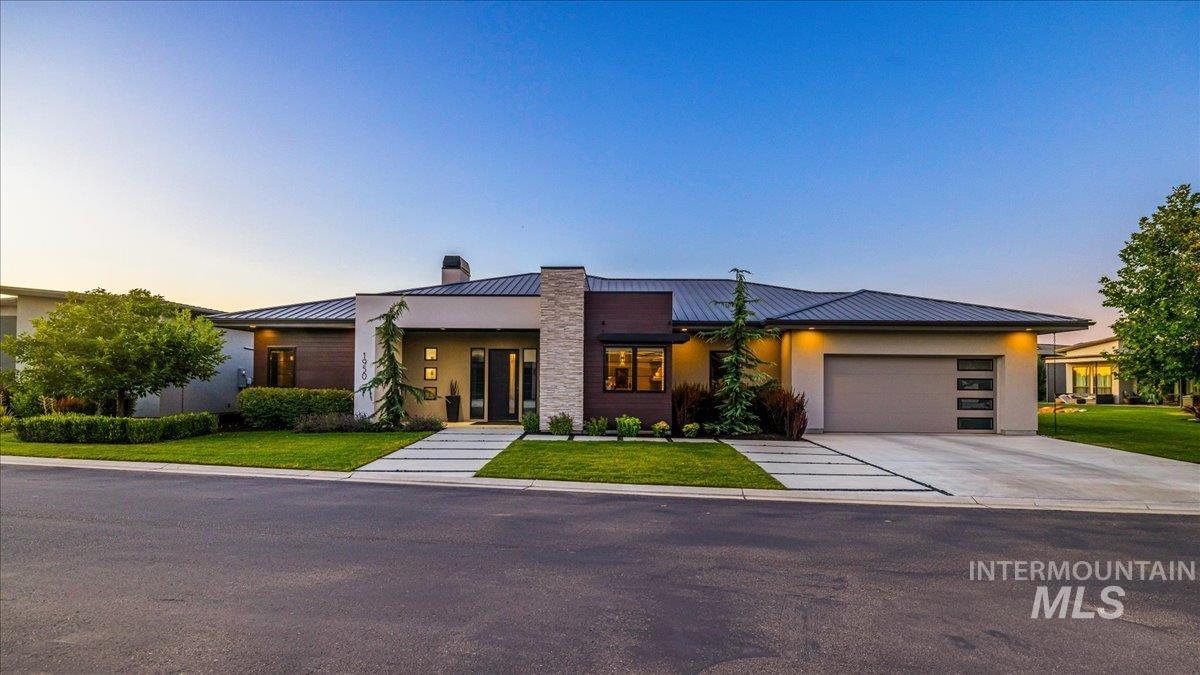 Modern home featuring a standing seam roof, a metal roof, a garage, a chimney, and concrete driveway
