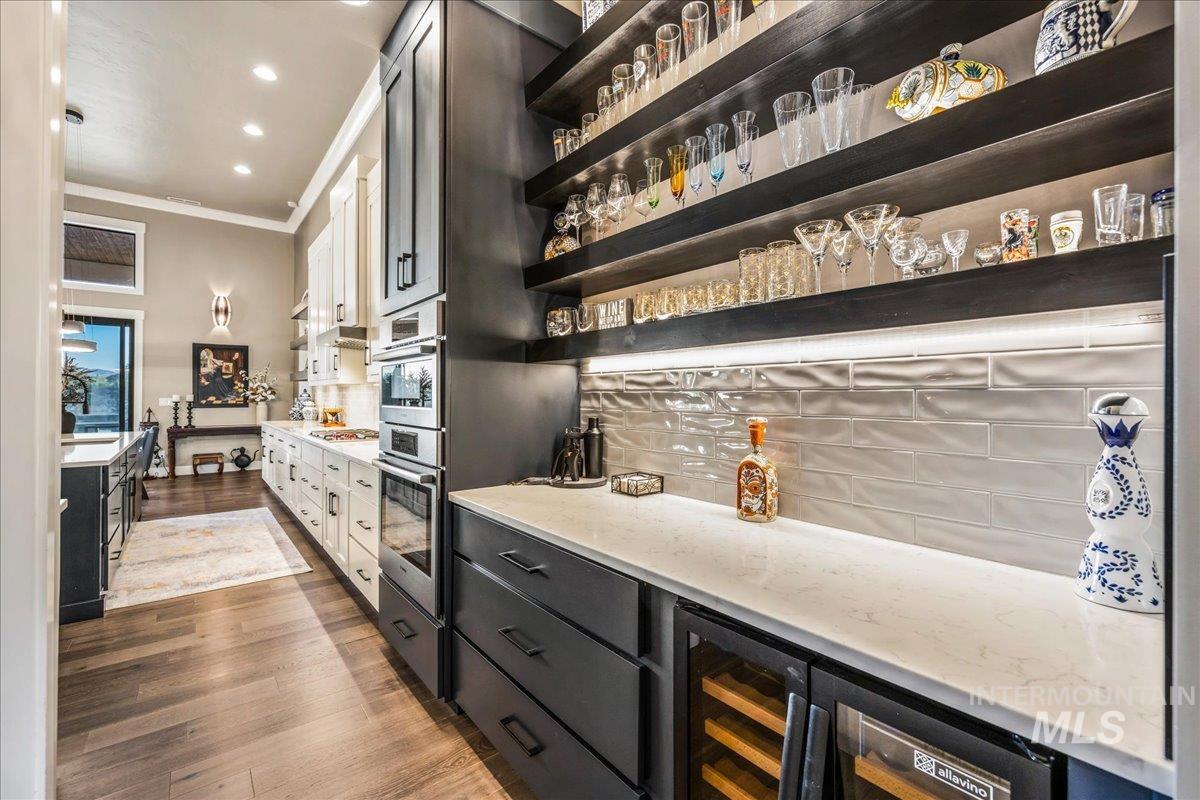 Indoor dry bar featuring crown molding, dark wood-style floors, wine cooler, tasteful backsplash, and recessed lighting