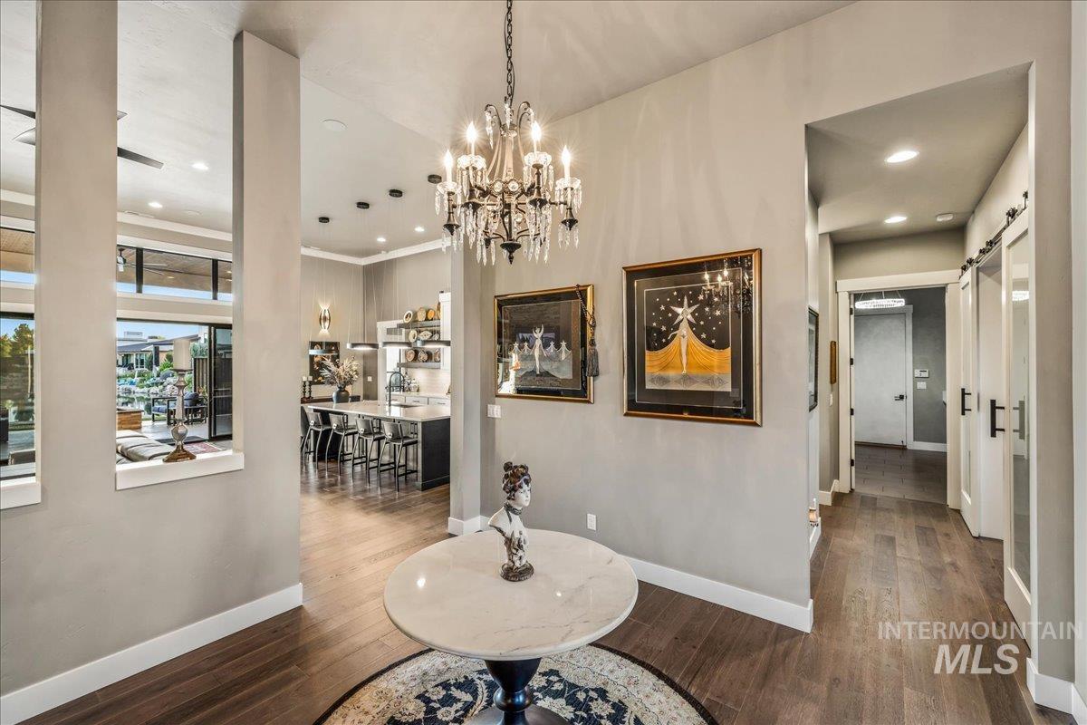 Hall with a barn door, wood finished floors, recessed lighting, and a chandelier